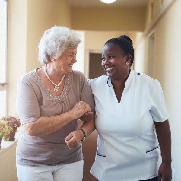 nurse walking down hallway with elderly woman