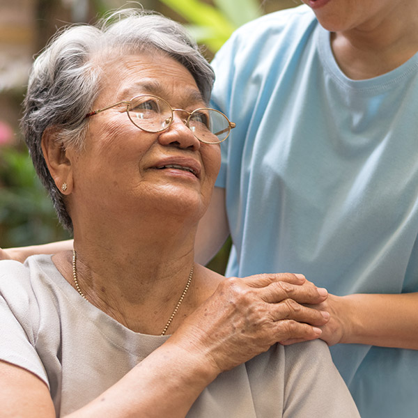 carer hand holding elder hand woman in hospice care